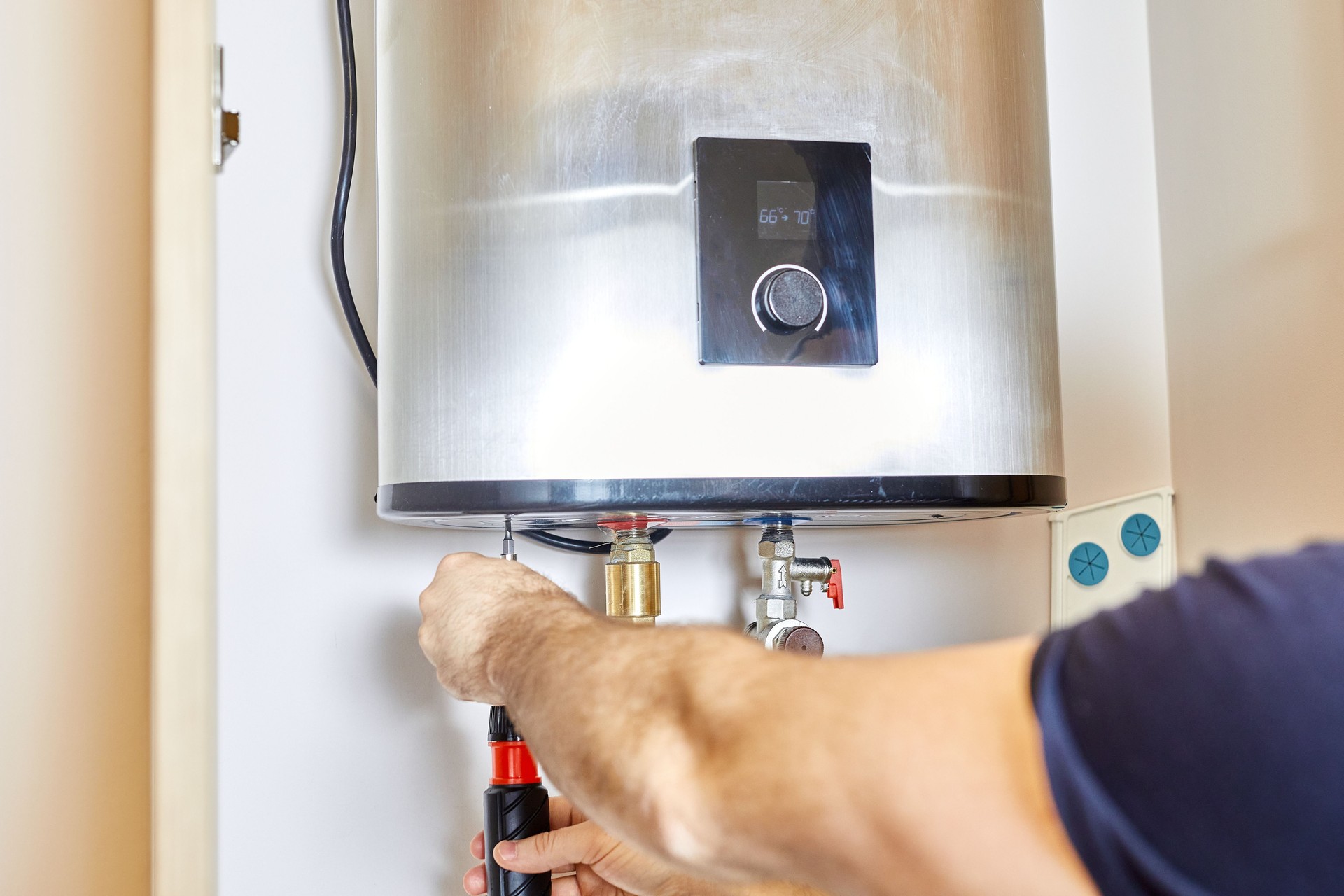 L’homme serre l’écrou du tuyau dans le système de chauffage de l’eau. Le maître installe le chauffe-eau. Le concept d’entretien de la salle de bain.